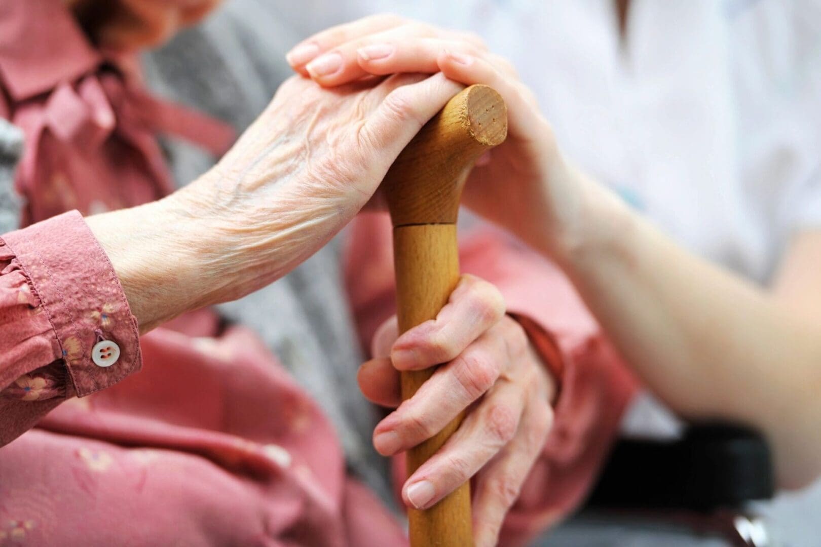 A person holding onto a wooden cane