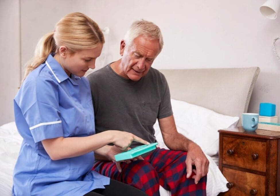 A nurse is helping an older man with his medical equipment.